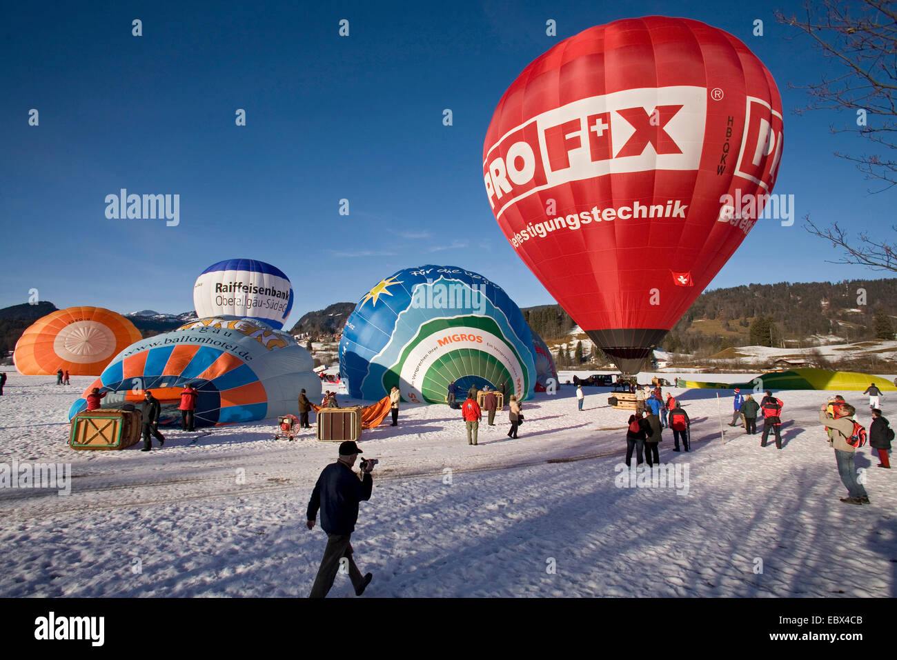 hot-air balloon festival on a snow field with several balloons being prepared for the start and a lot of spectators, Germany, Bavaria, Allgaeu, Oberstdorf Stock Photo