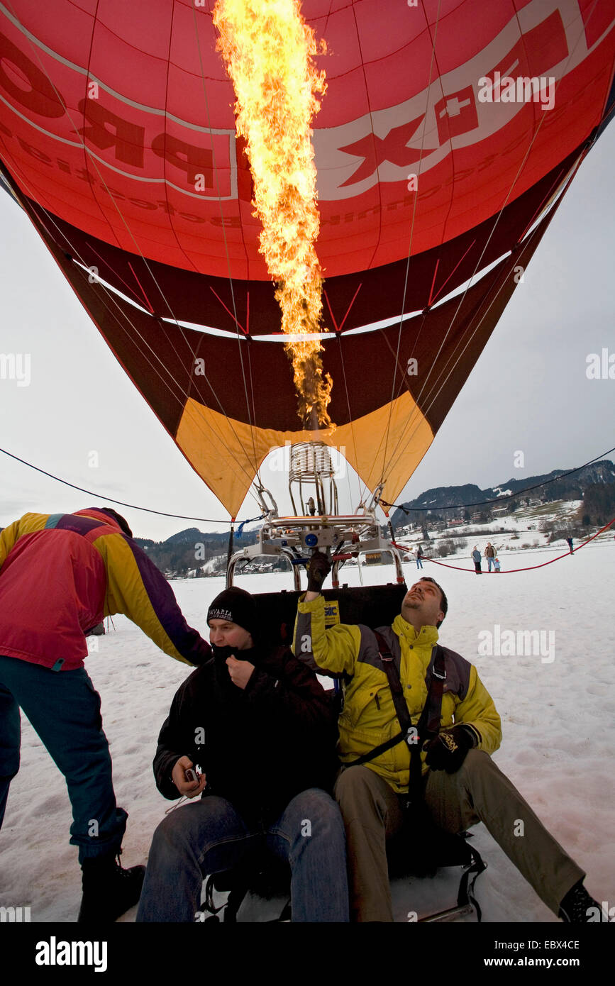 hot-air balloon standing on snow field with two men on bord while being fired for the start, Germany, Bavaria, Allgaeu, Oberstdorf Stock Photo
