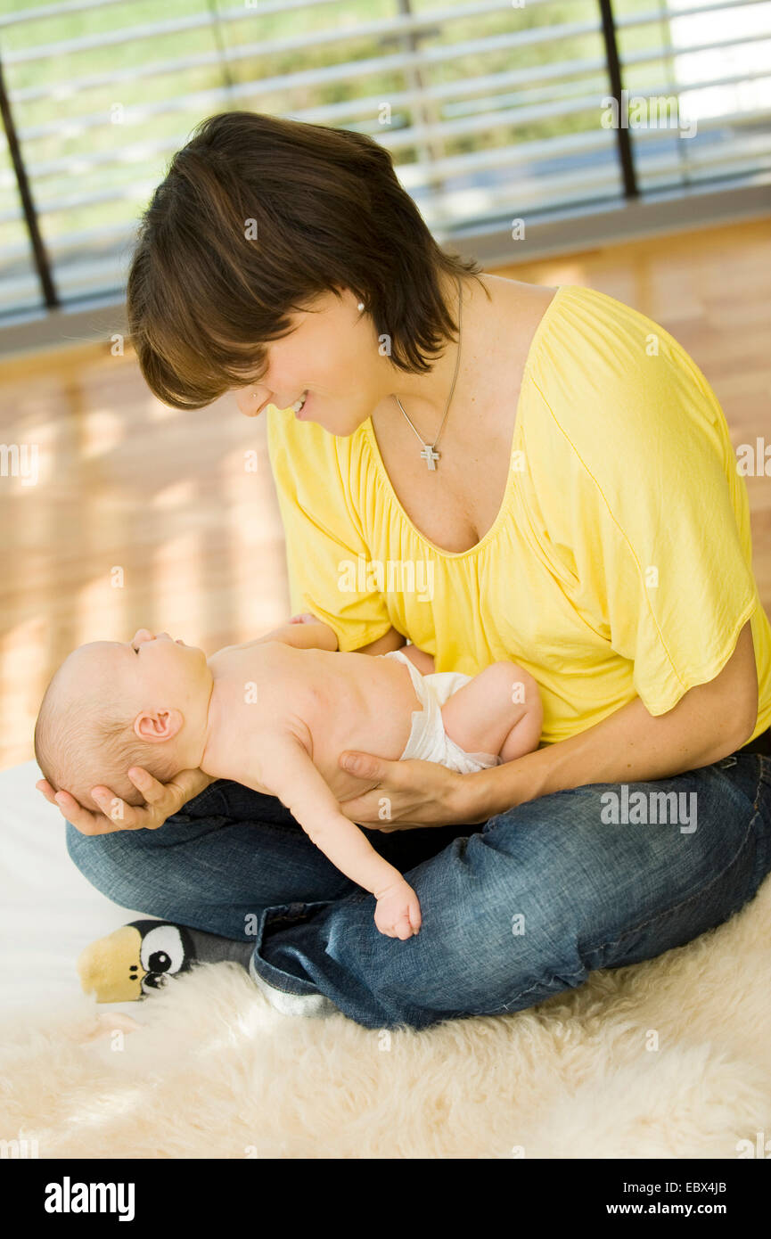mother with baby in her arms sitting o the ground Stock Photo