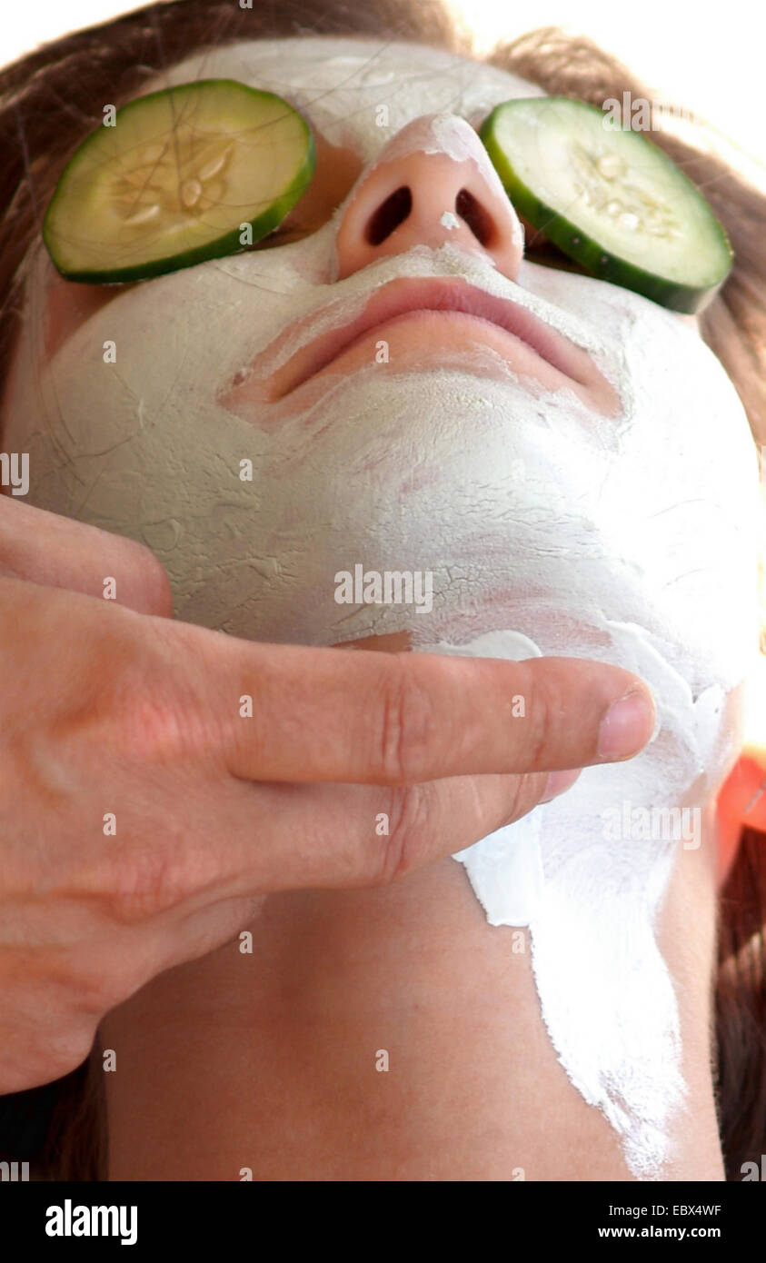 woman getting a face pack with cucumber slices on the eyes Stock Photo