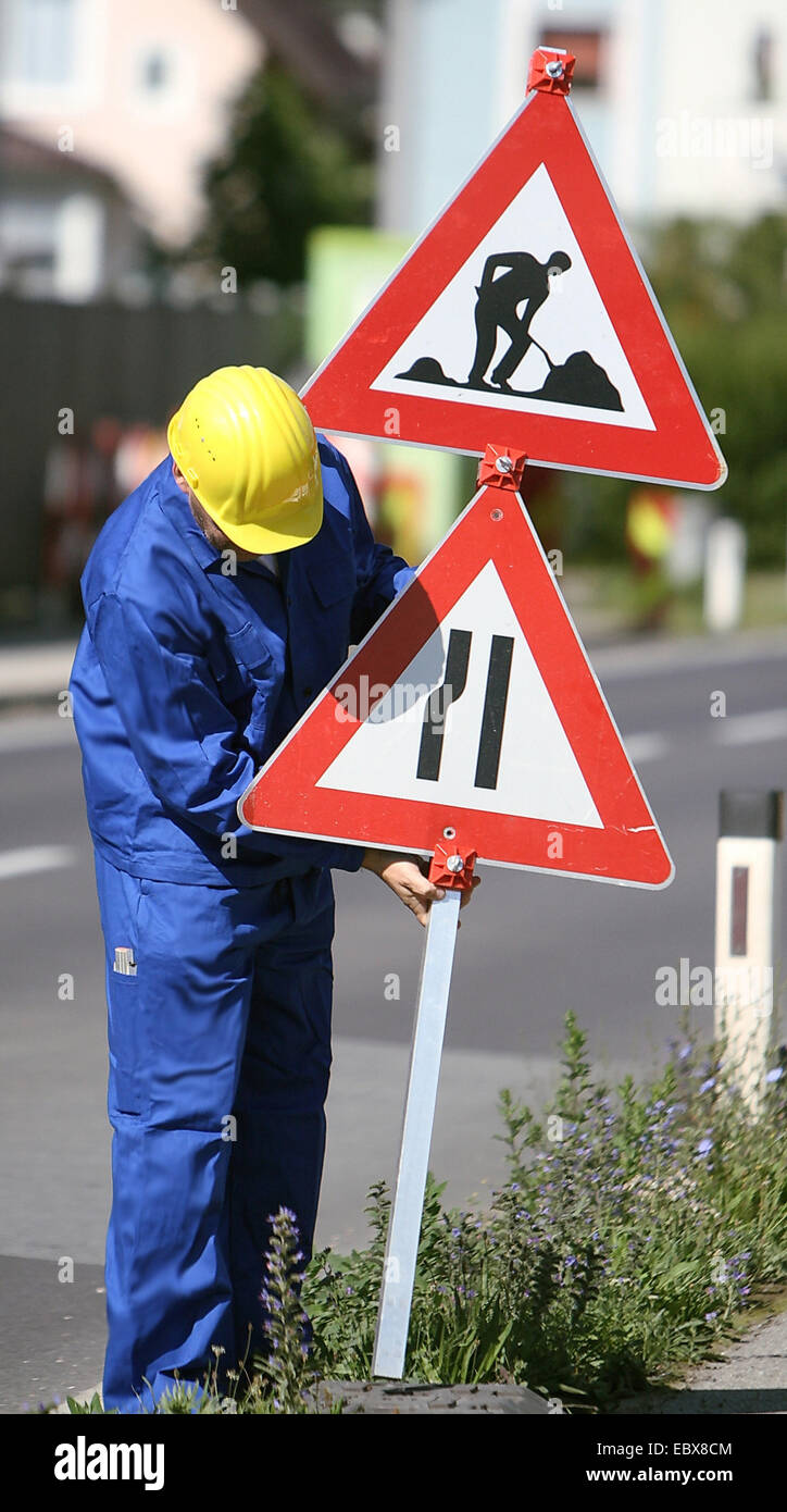 construction worker puts up a sign near the street Stock Photo
