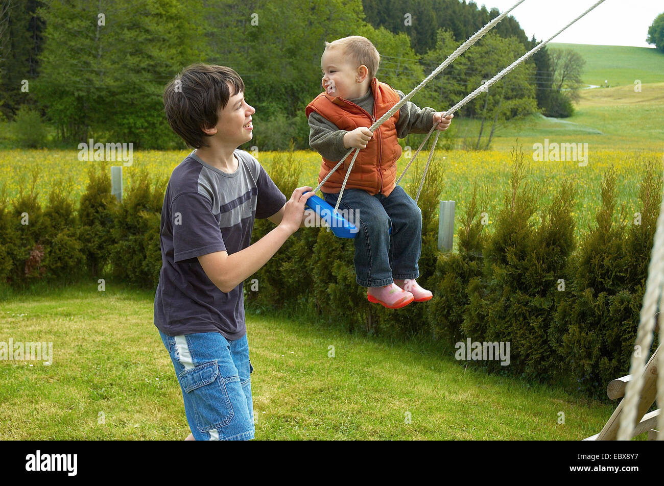 Brothers are swinging together in a garden Stock Photo