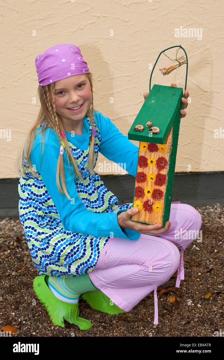 girl in colourful clothes presenting a self-made breeding boxes for wild bees, Germany Stock Photo