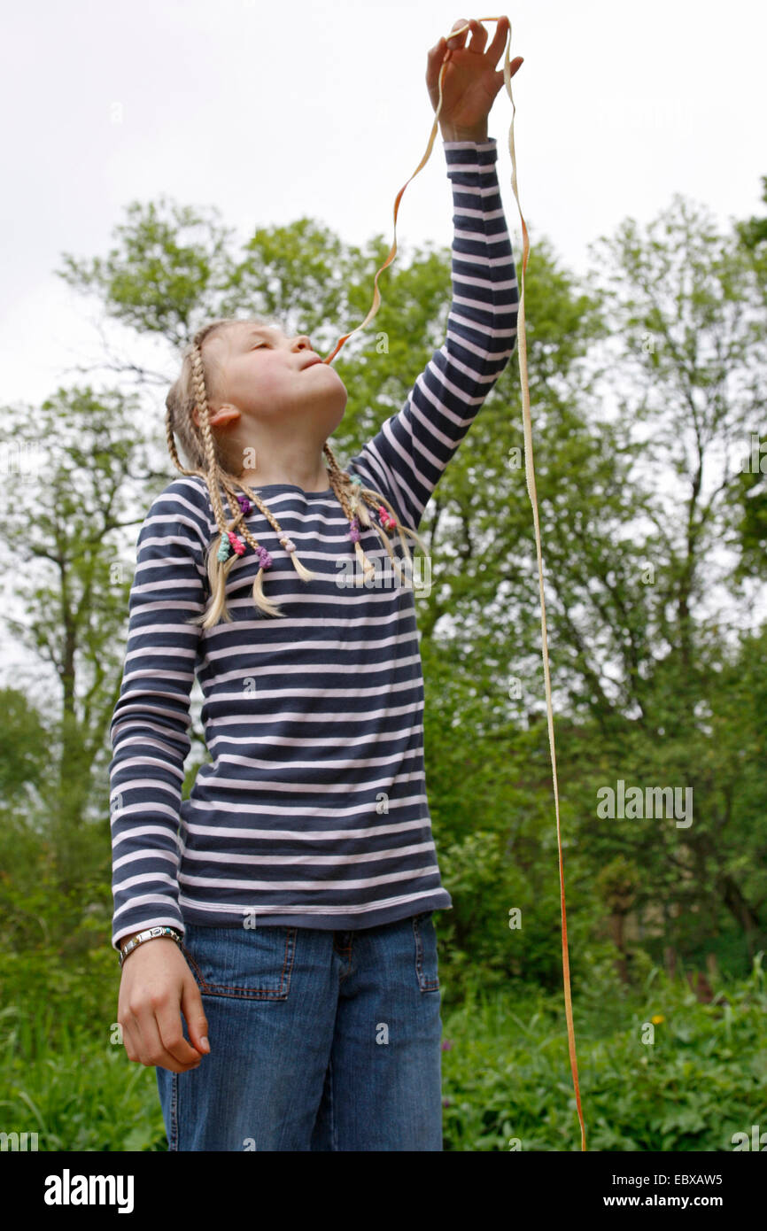 girl is eating a long strip of apple peel, Germany Stock Photo