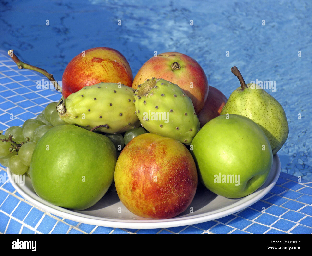 fruits (apples, pears, grapes and prickly pears) on  plate by the pool Stock Photo