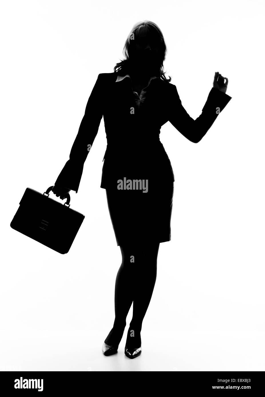 silhouette of a young woman with a small briefcase lifting a hand Stock Photo