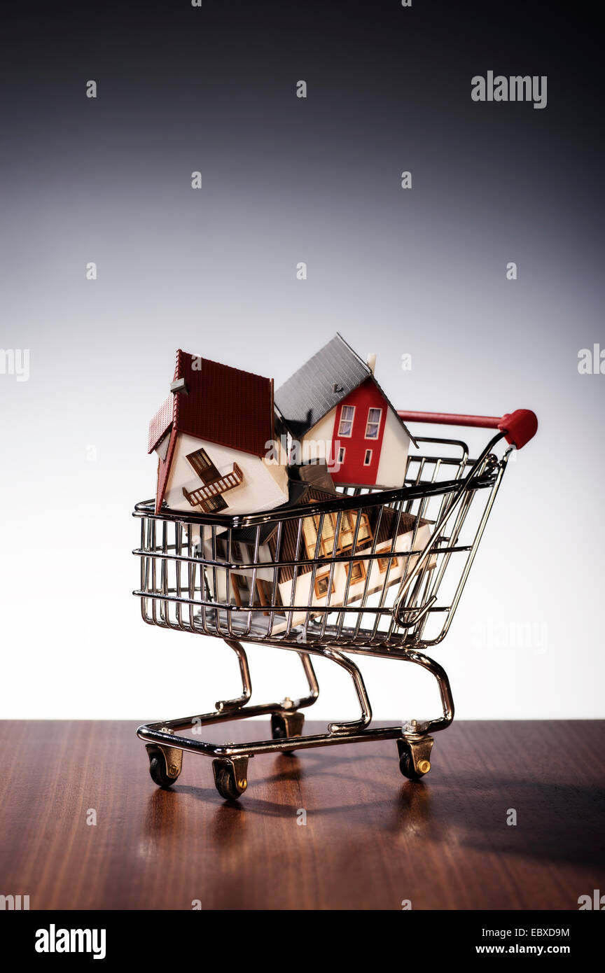 Three models of houses are stacked in a shopping cart. Stock Photo