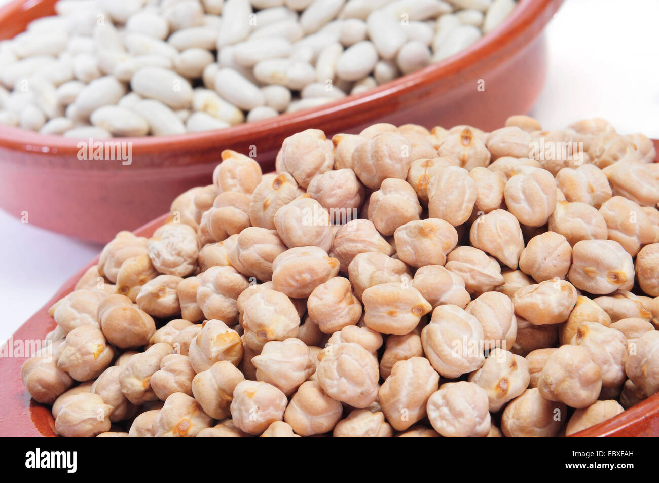 closeup of some earthenware bowls with dry chickpeas and white beans Stock Photo