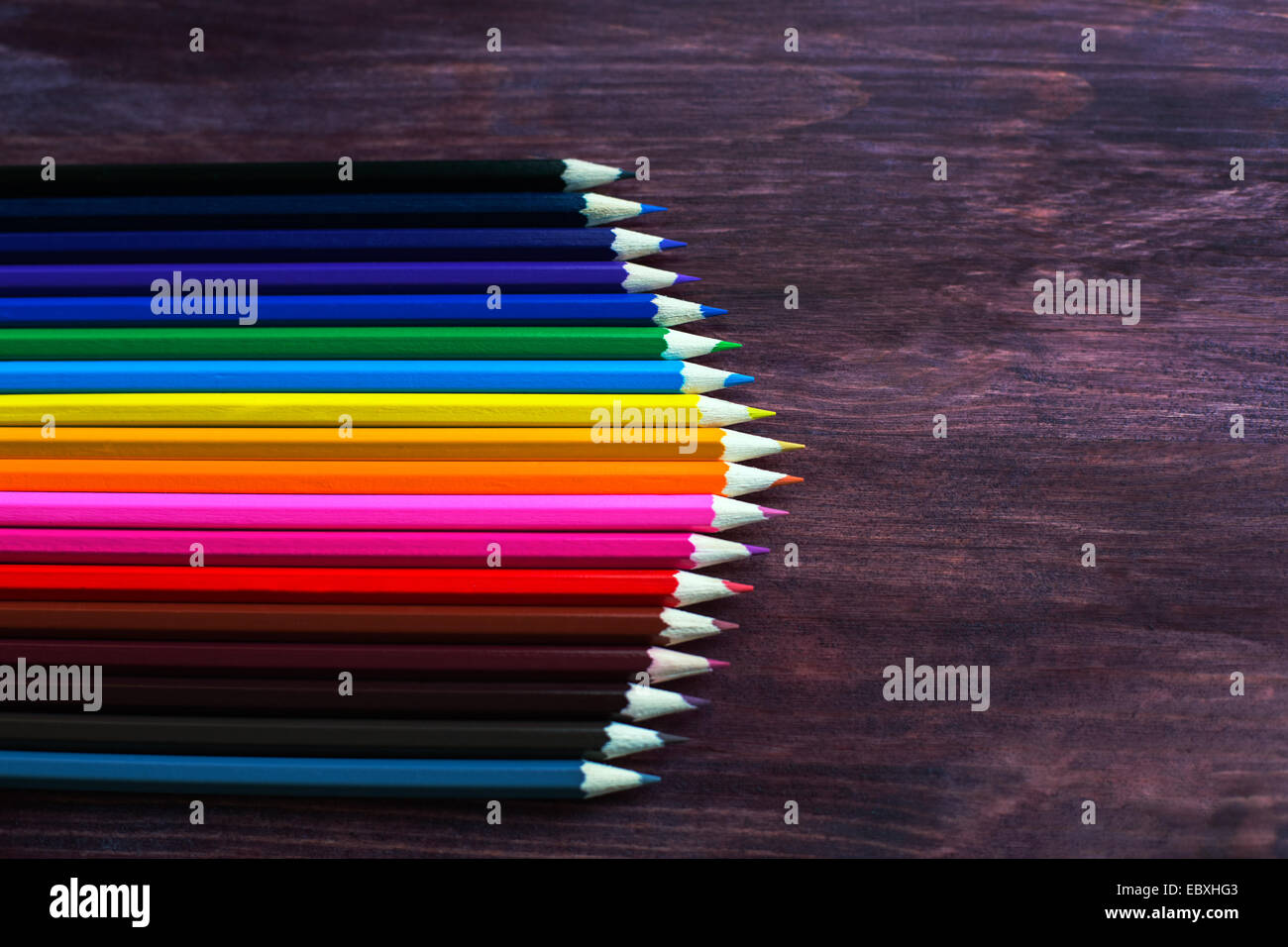 coloured pencils in a row on dark background Stock Photo