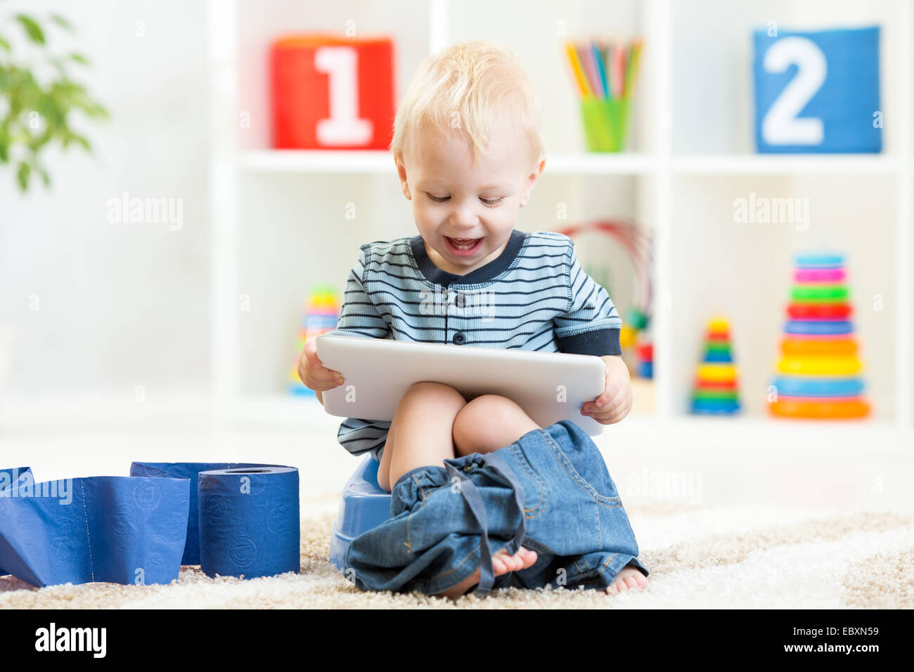 smiling child sitting on chamber pot with toilet paper Stock Photo