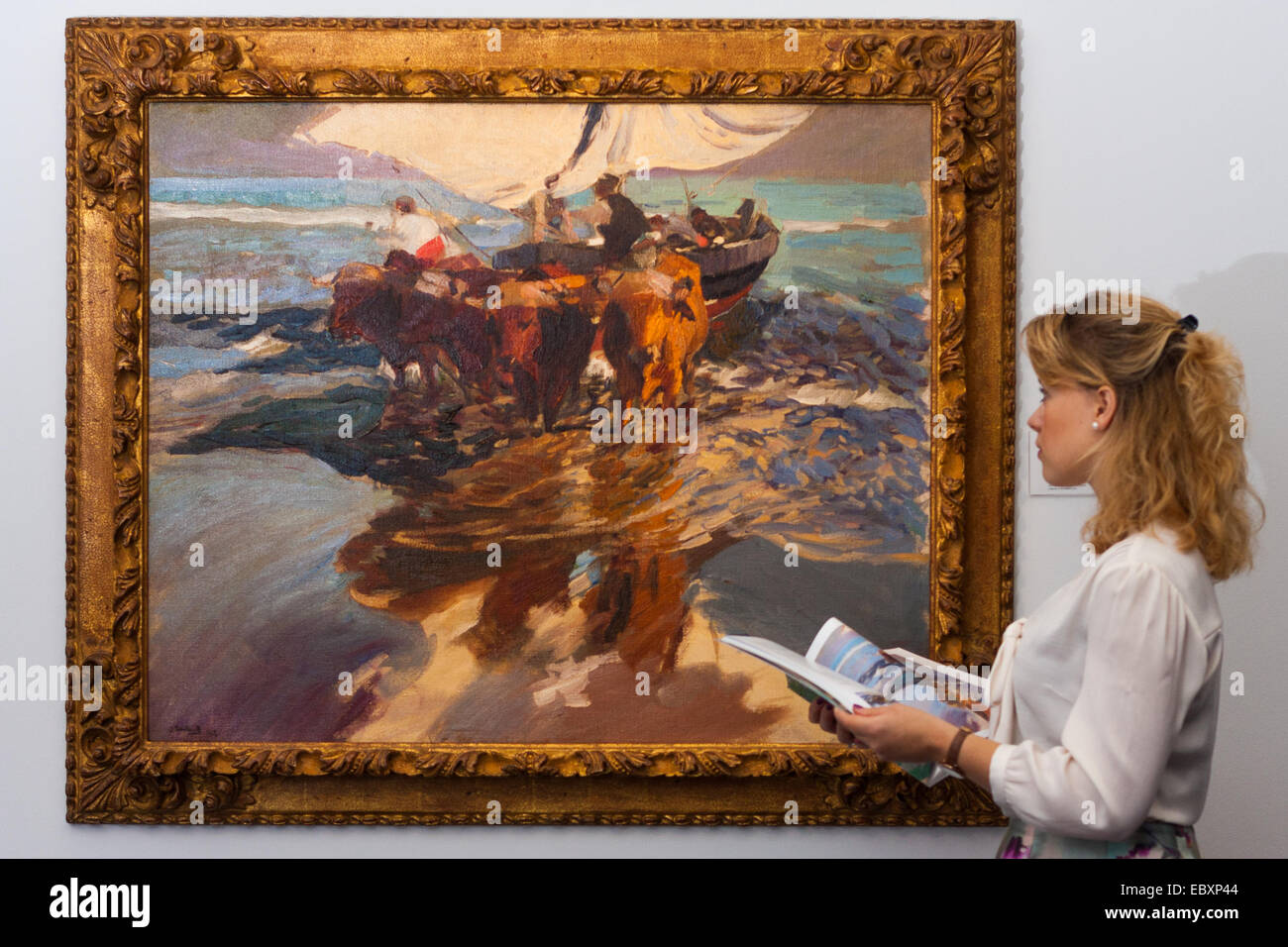 London, UK. 5th December, 2014. World renowned aution house Sotheby's is to offer a collection of British and Continental masters to be sold at auction on December 10th 2014. PICTURED: A woman admires the bold brushstrokes of Joaquin Sorolla's Vuelta de la Pesca, Playa Valencia (The return from fishing, Valencia beach) which is expected to fetch between £1,4 and 1.8million at auction. Credit:  Paul Davey/Alamy Live News Stock Photo