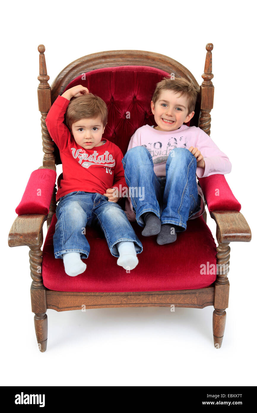 two brother sitting on a velvet armchair Stock Photo
