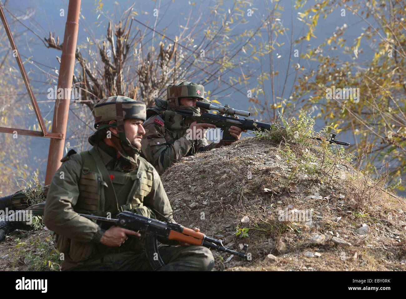 (141205) -- SRINAGAR, Dec. 5, 2014 (Xinhua) -- Indian army troopers take position during a gunfight in Gingal area of Mohar village near garrison Uri town, about 95 km north of Srinagar, summer capital of Indian-controlled Kashmir, Dec. 5, 2014. At least 17 people, including eight Indian troopers and three policemen, were killed Friday in a predawn militant suicide attack on an Indian military fortification near Line of Control (LoC) dividing Kashmir, officials said. (Xinhua/Javed Dar)(bxq) Stock Photo