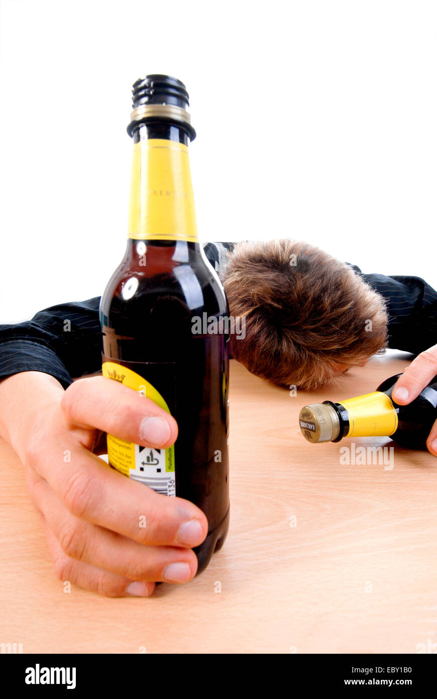 drunken teenager sitting at a desk with beer bottles Stock Photo