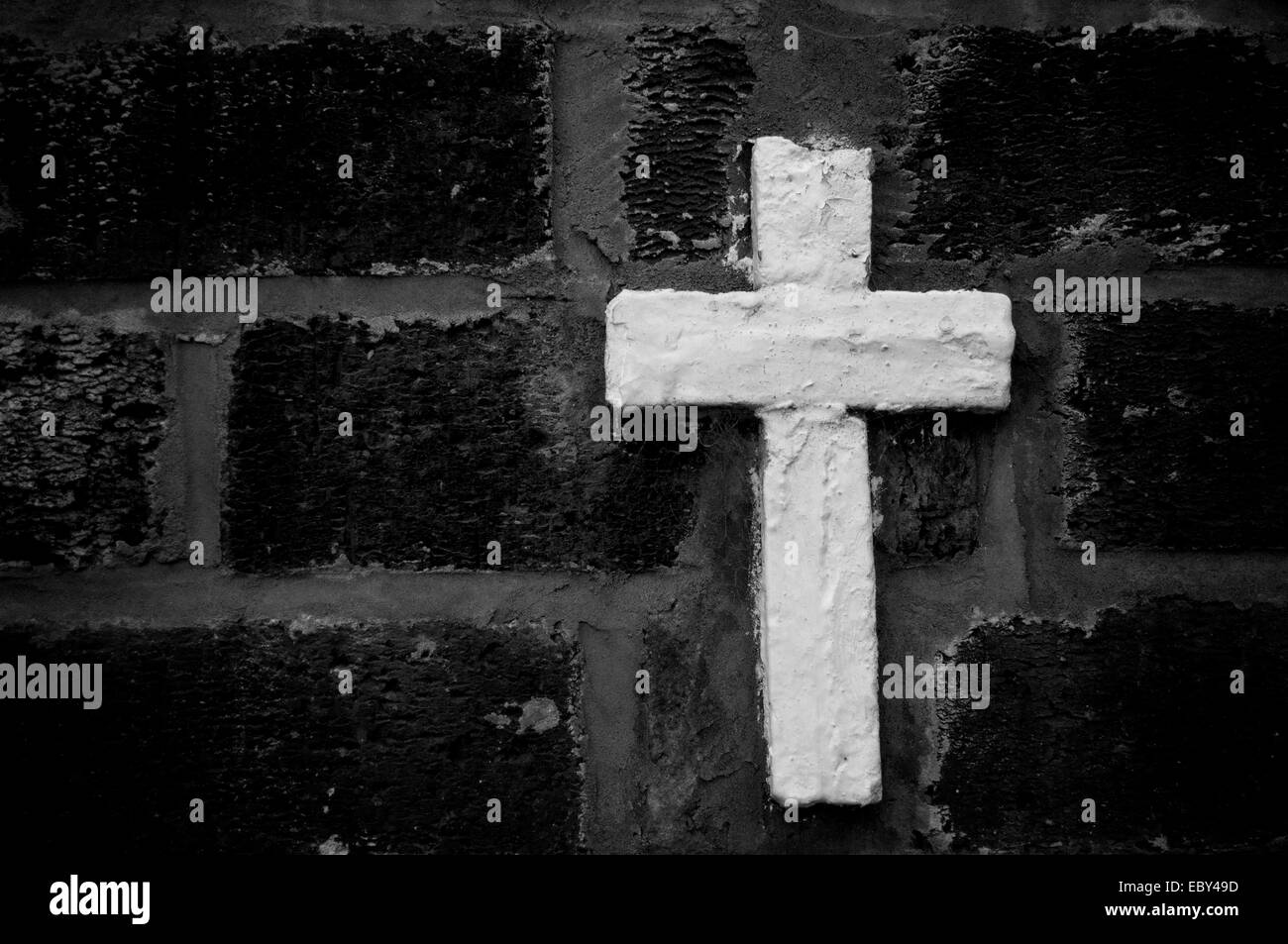 A white stone cross against a black brick wall Stock Photo Alamy