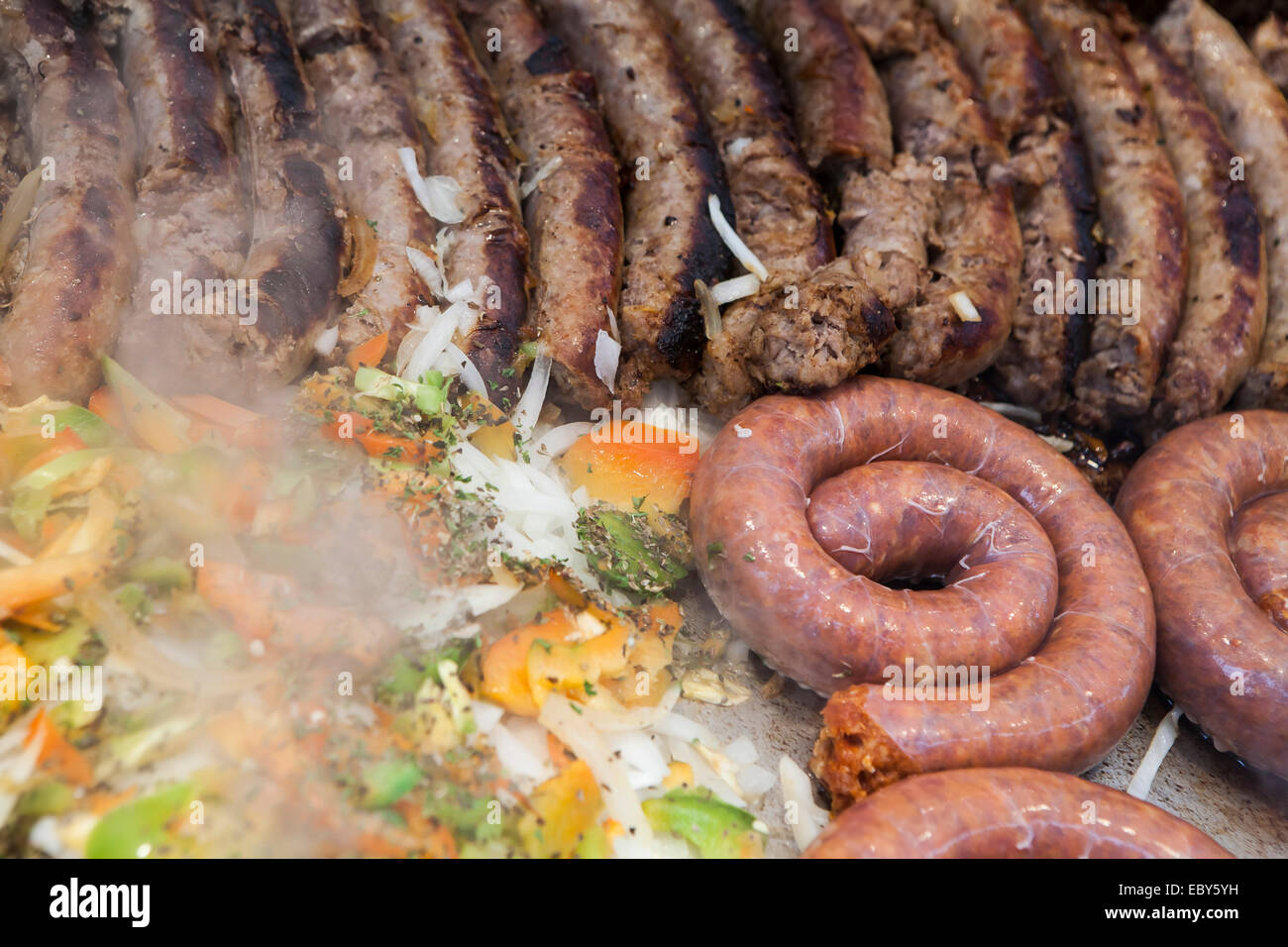 Italian sausages, peppers and onion cooking on a grill at a street