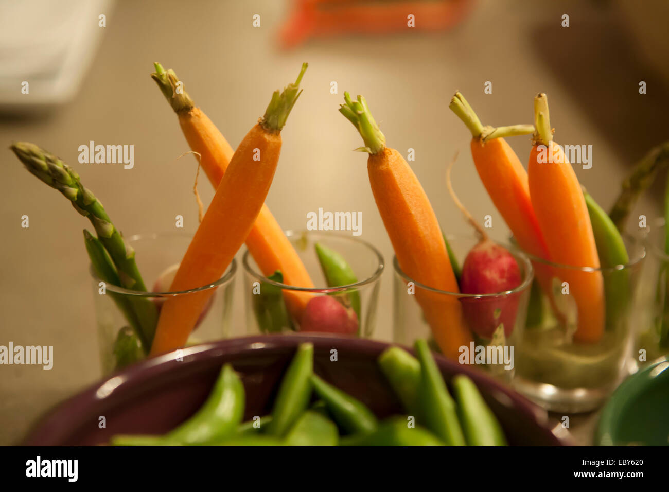 A display of carrots, asparagus, radishes and sugar snap peas in snall glasses. Stock Photo