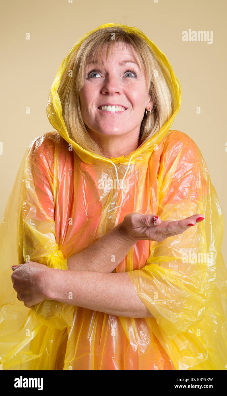 Woman wearing a yellow Poncho in wet weather Holding her hand out to check if it is raining Stock Photo