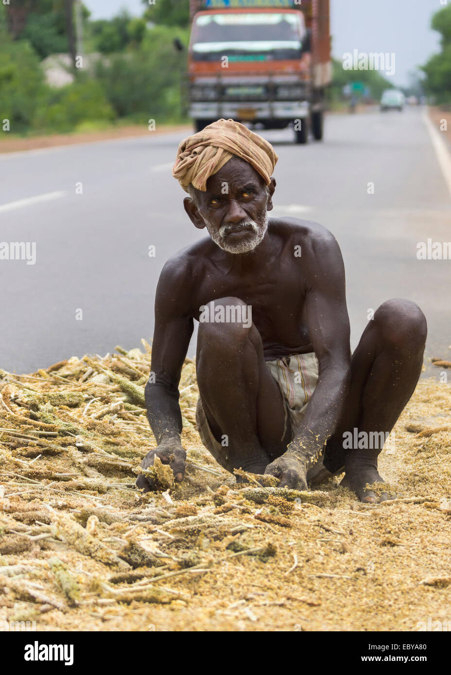 Old dark-skinned farmer works his mellet on public road. Stock Photo
