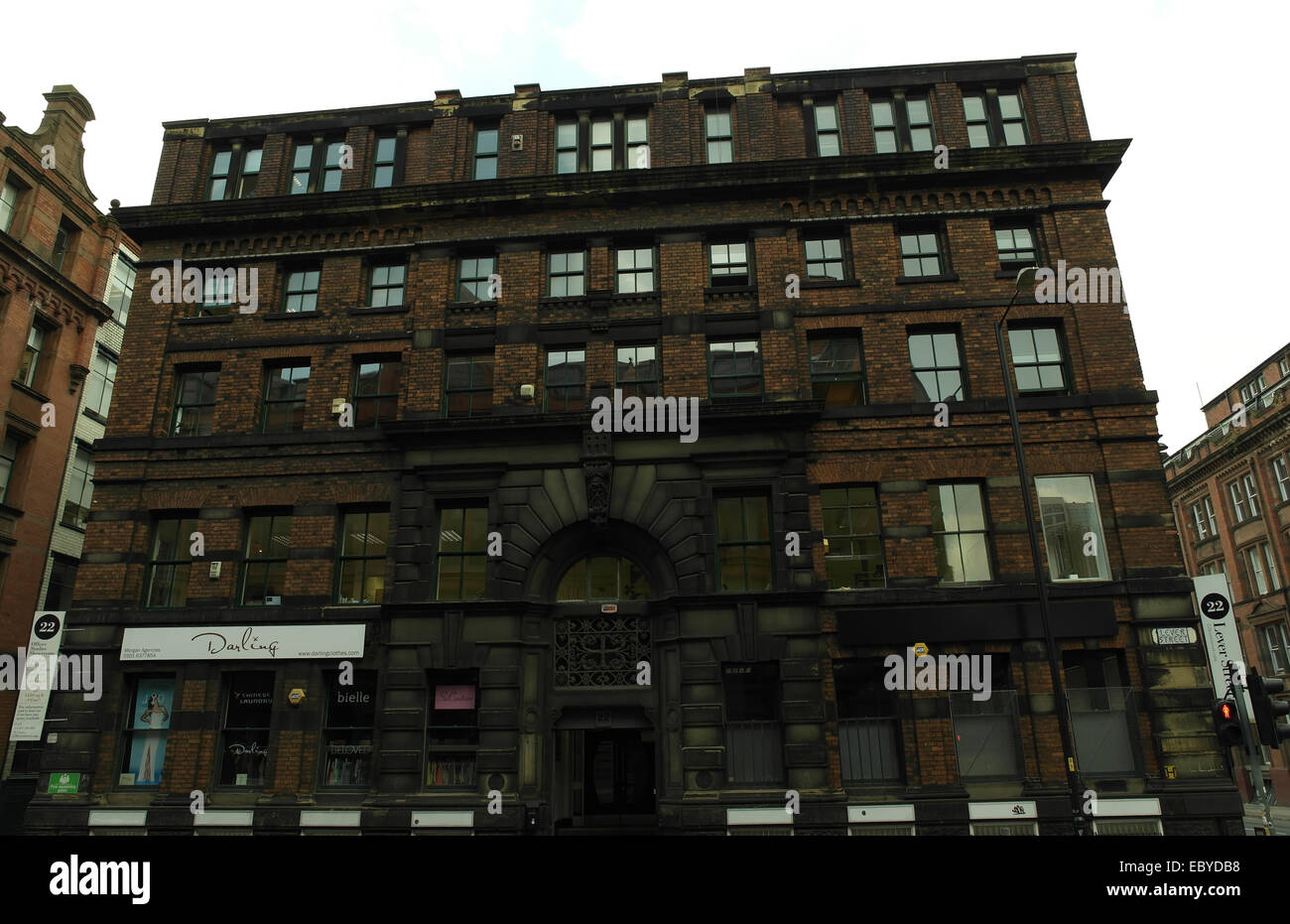 Grey sky view 10 windows long, red bricks facade, large stone archway entrance, Grade 2 listed '22 Lever Street', Manchester Stock Photo