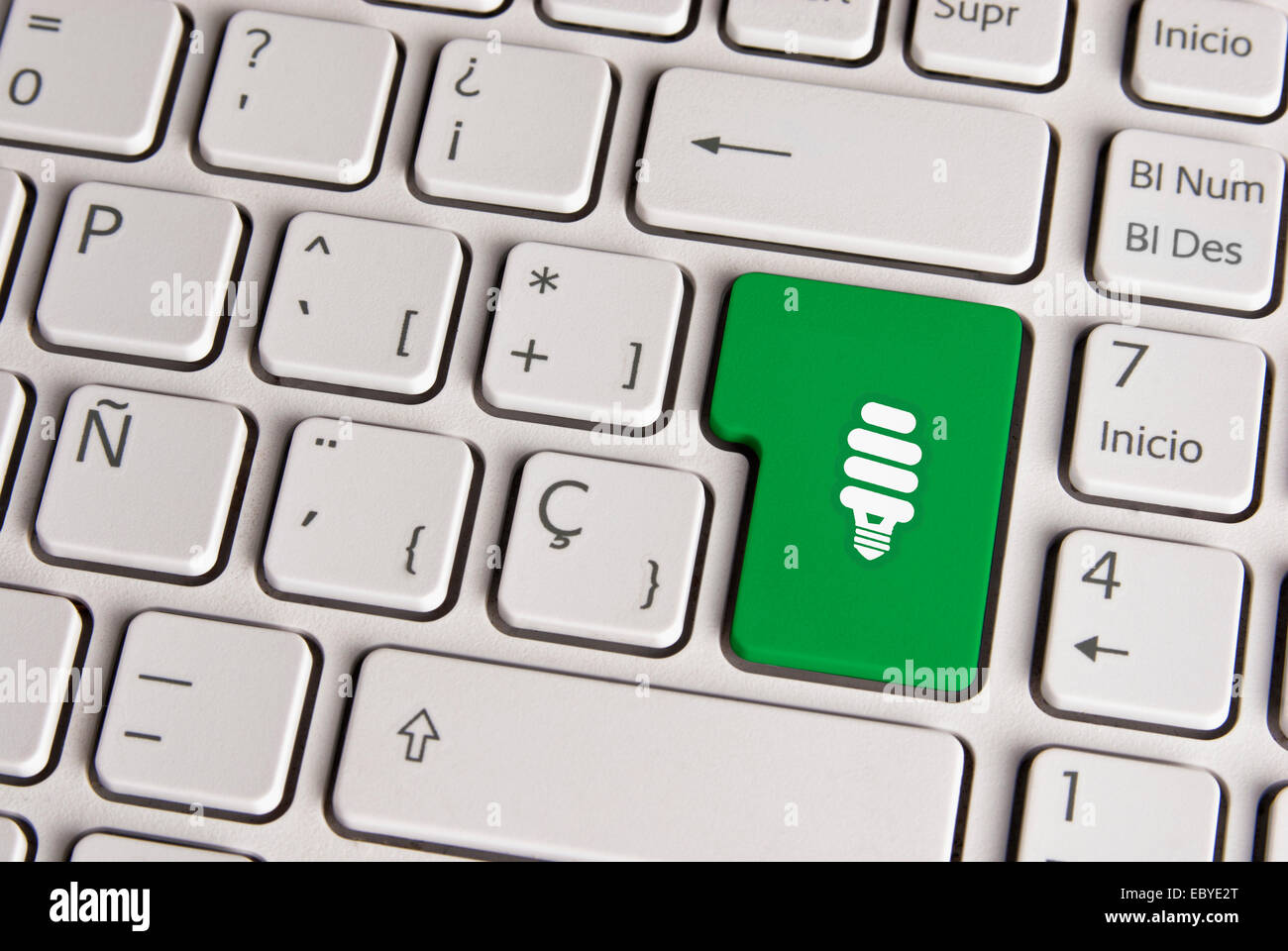 Spanish keyboard with eco energy light save bulb icon over green background button. Image with clipping path for easy change the Stock Photo