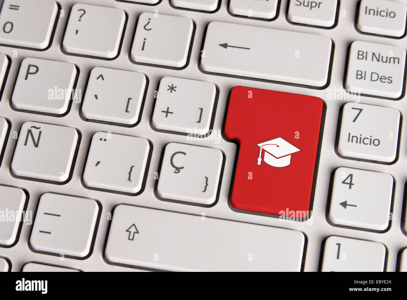 Spanish keyboard with education graduation hat icon over red background button.  Image with clipping path for easy change the ke Stock Photo