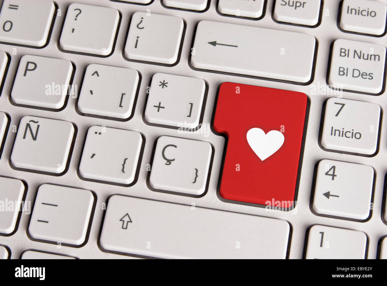 Spanish keyboard with love concept heart shape icon over red background button. Image with clipping path for easy change the key Stock Photo