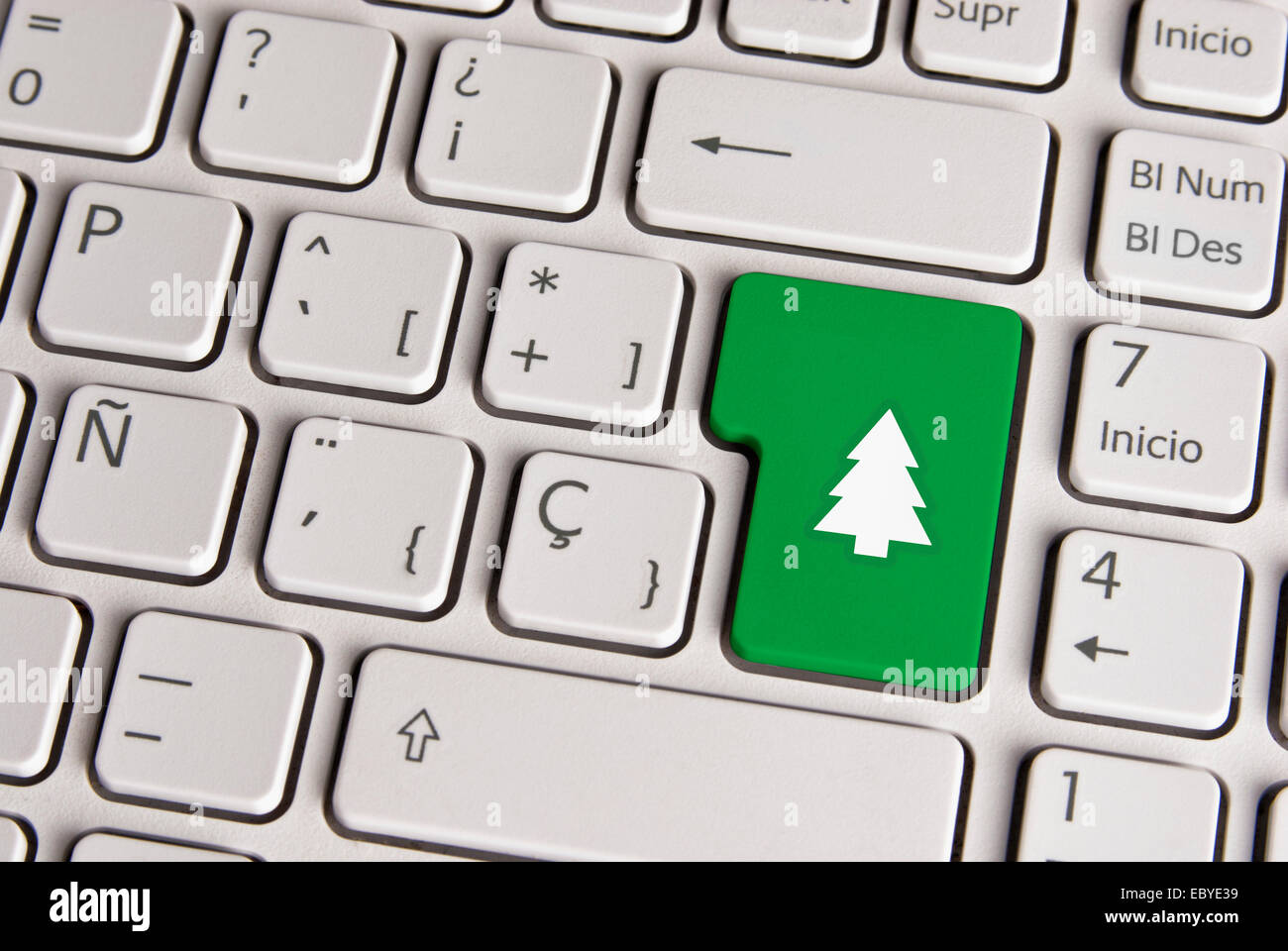 Spanish keyboard with Merry Christmas tree icon over green background button. Image with clipping path for easy change the key c Stock Photo