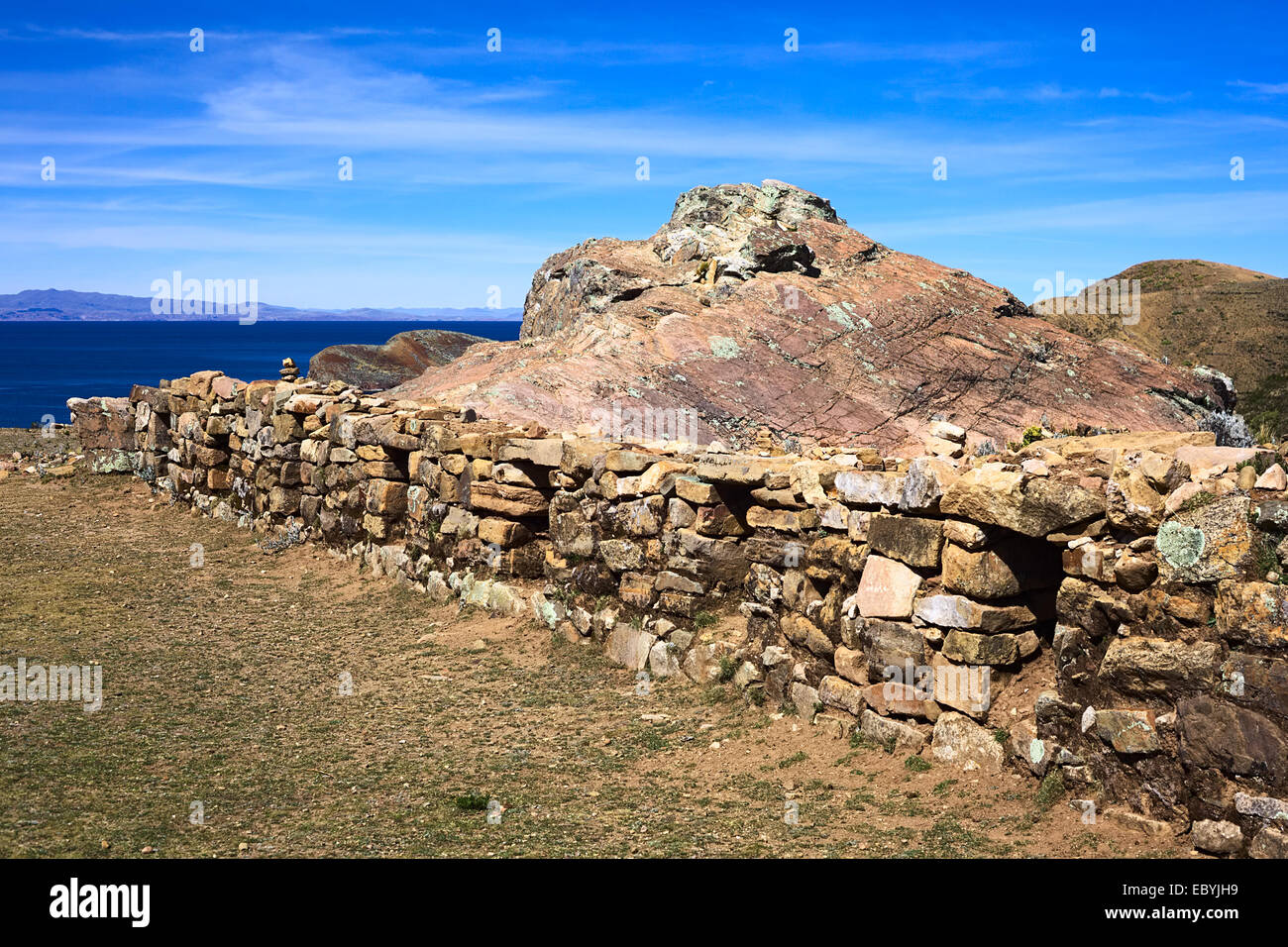 Low stone wall with openings beside the Rock of the Puma, the sacred rock formation on Isla del Sol in Lake Titicaca, Bolivia Stock Photo