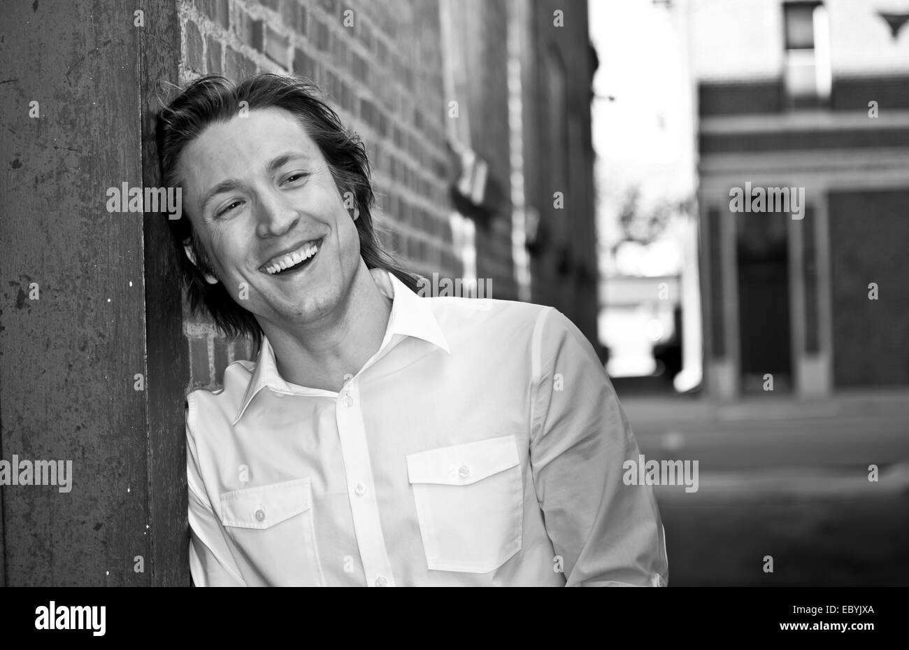 Black and white image of a smiling young guy in an urban environment. Stock Photo