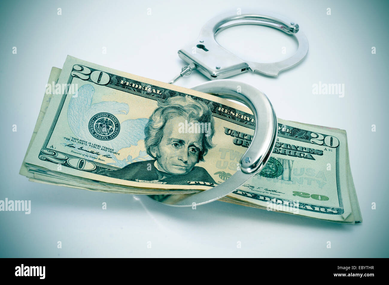 a pair of handcuffs and some dollar bills depicting the idea of arrest