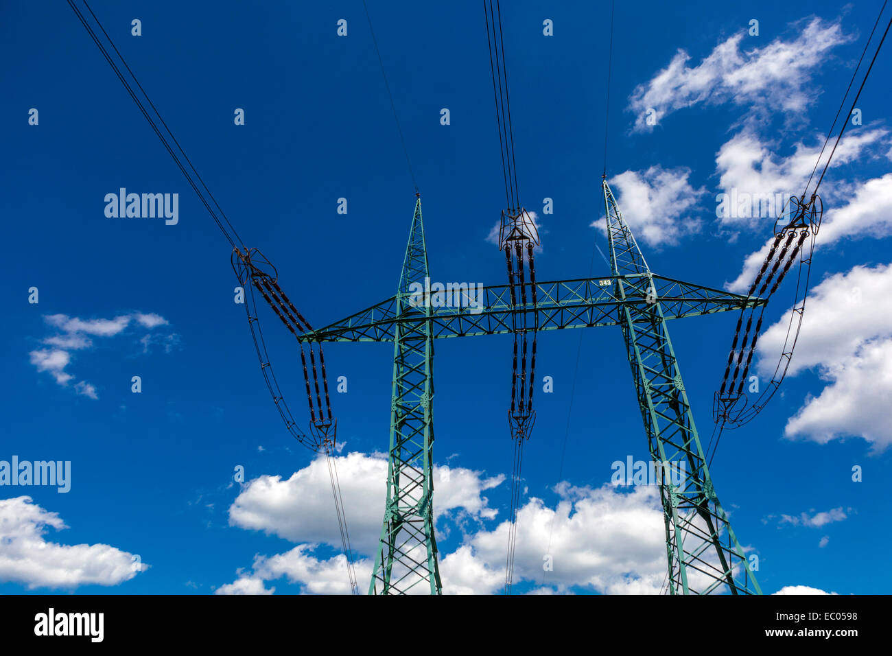 Power lines pylon in blue sky and clouds background, High Voltage mast wires in sky Stock Photo