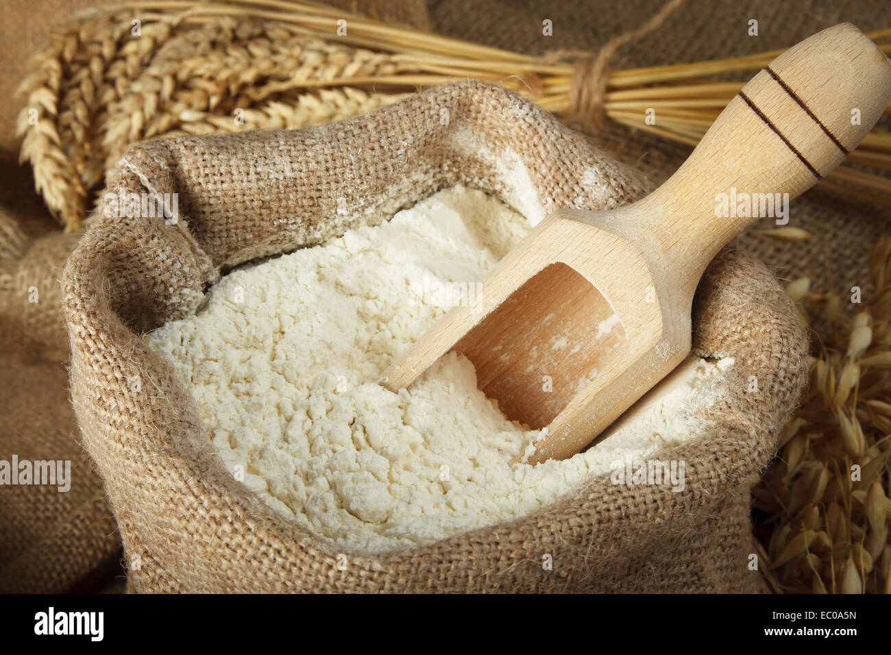Flour in burlap bag and wooden spoon Stock Photo