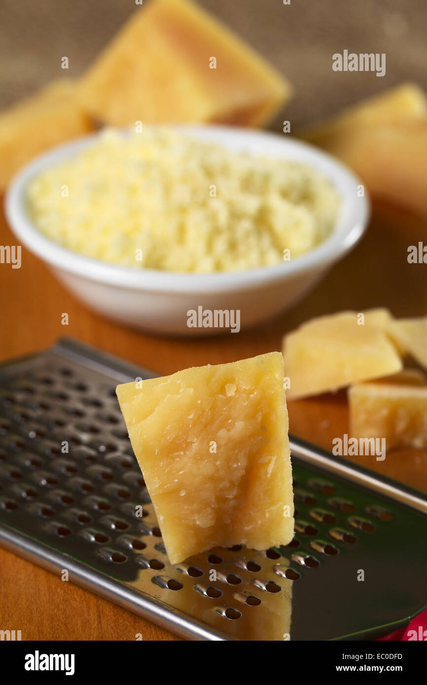 Italian hard cheese on rasp with grated cheese in bowl in the back on