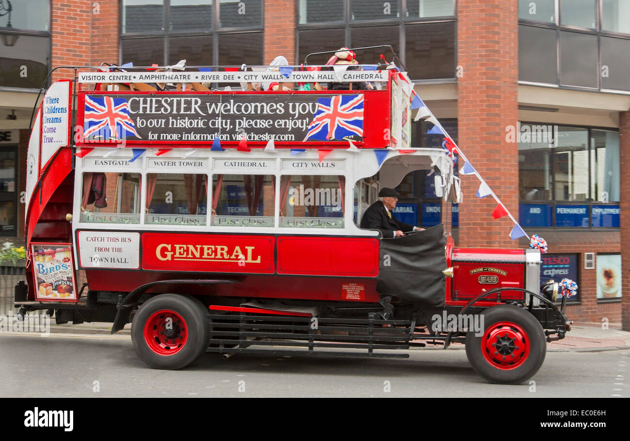 Bright red open top double decker Bedford tour bus, replica of 1910 B-type motorbus, draped with British flags, in centre of city of Chester England Stock Photo