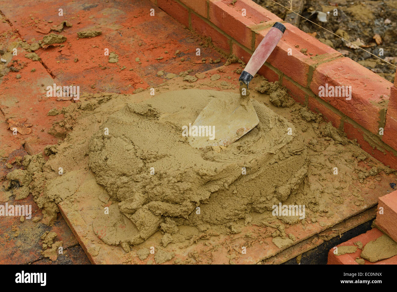 Bricklaying trowel and a board of mortar on a UK building site Stock Photo