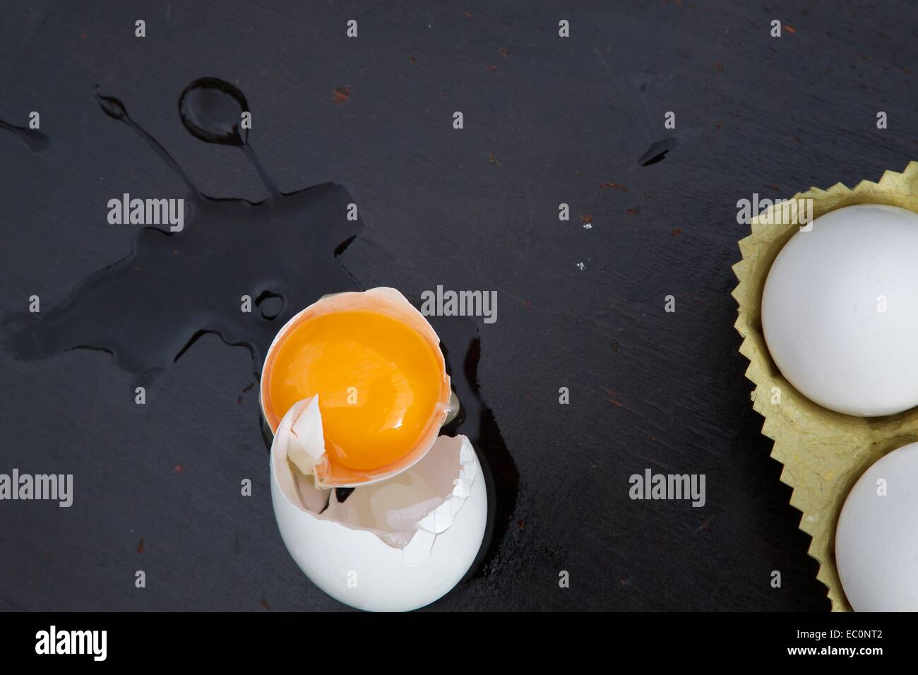 A broken egg on a black wooden surface Stock Photo - Alamy