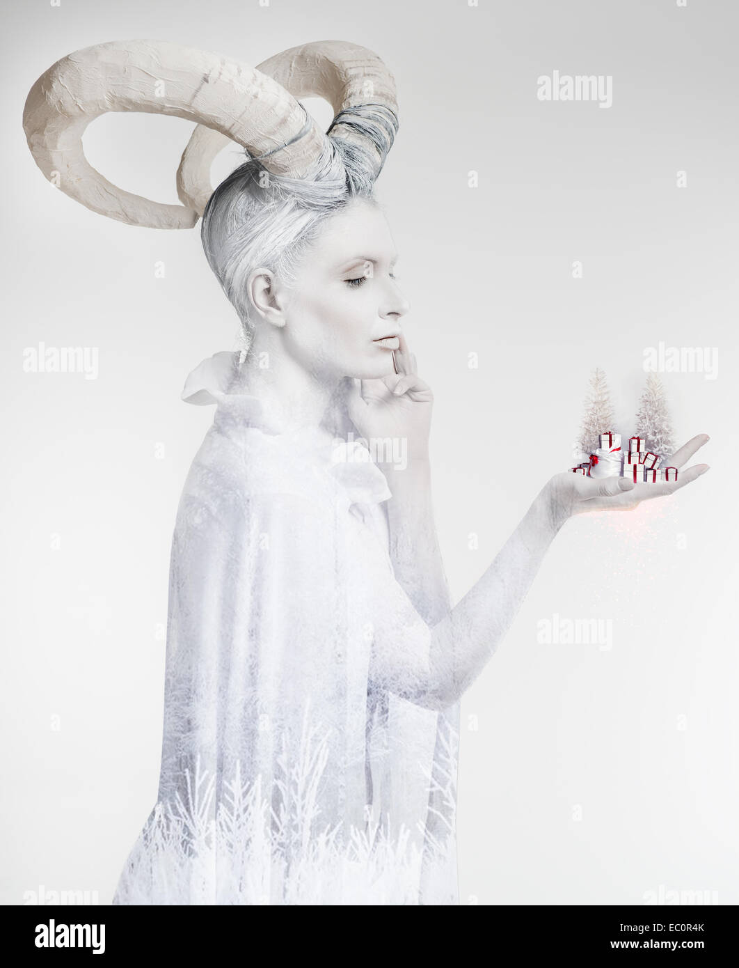 Woman with goat body-art holding small christmas trees and gift boxes Stock Photo