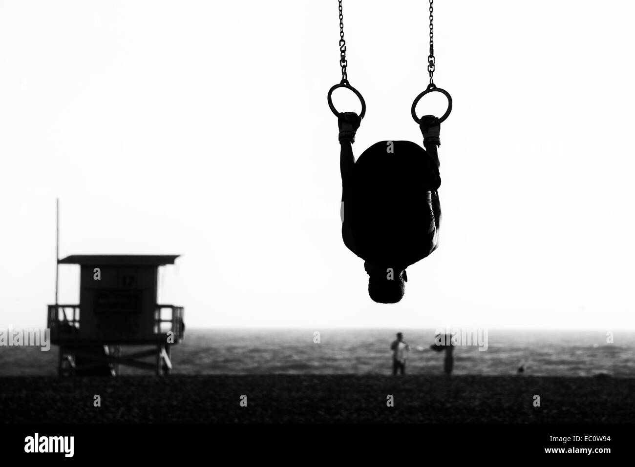Silhouette of a person swinging on rings on the beach, Santa Monica ...