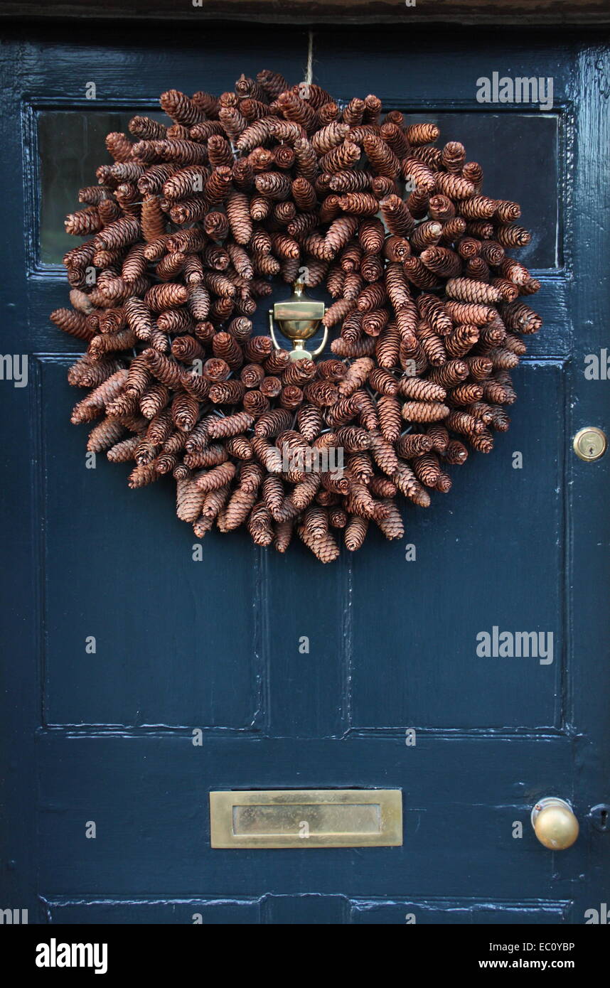 A rustic, cone-packed Christmas wreath hangs on the front door of a traditional English country home in the Peak District, UK Stock Photo