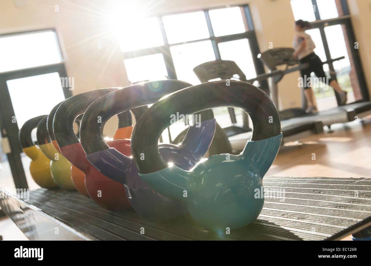 Kettle weights in a gym with a woman on a treadmill in a gym Stock Photo