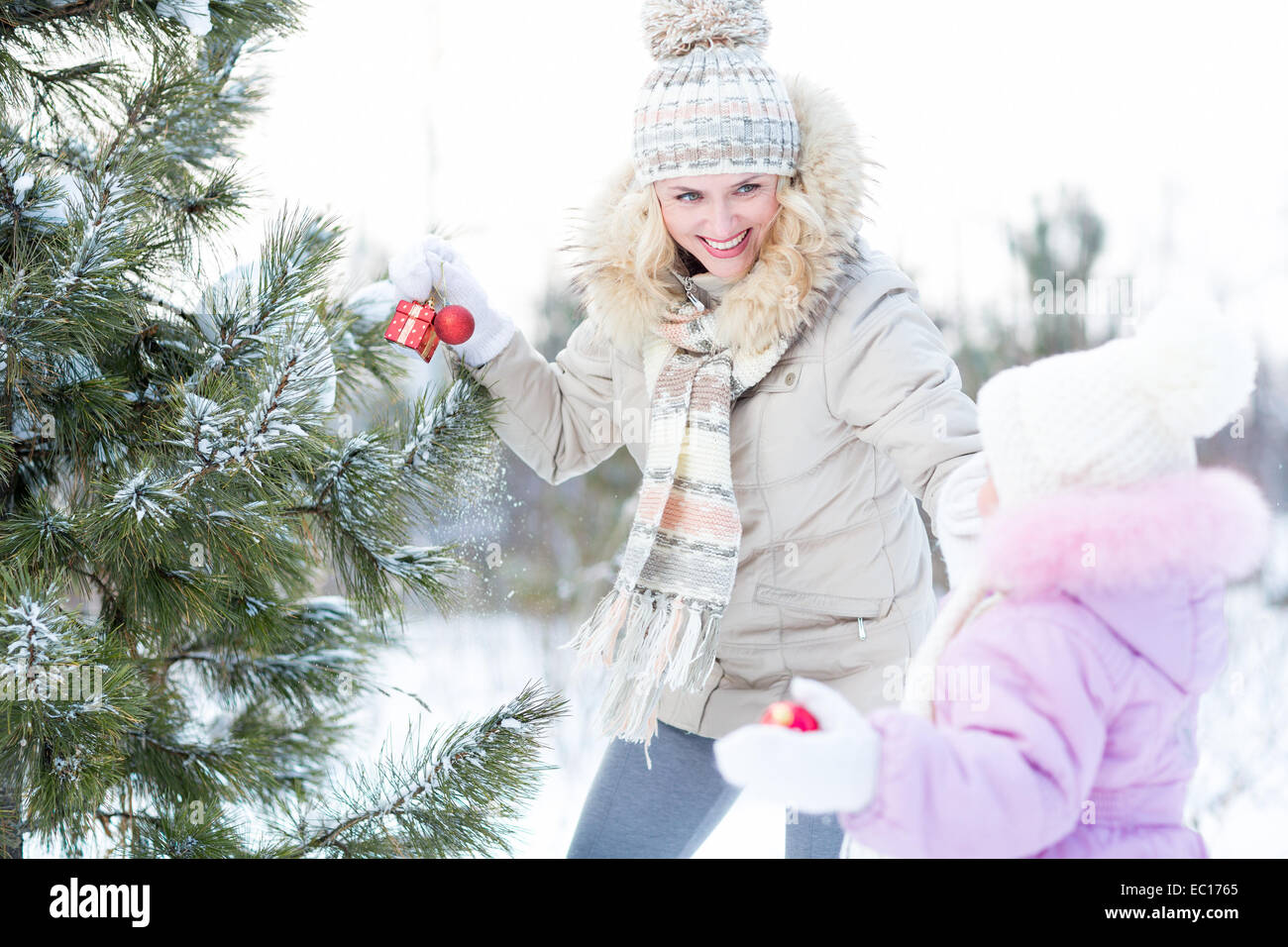 Happy mother and child playing with christmas tree decorations outdoor Stock Photo