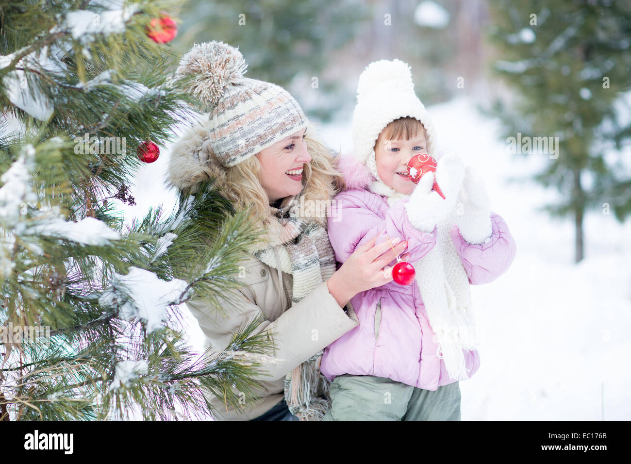 Happy parent and kid playing with christmas tree decorations outdoor Stock Photo