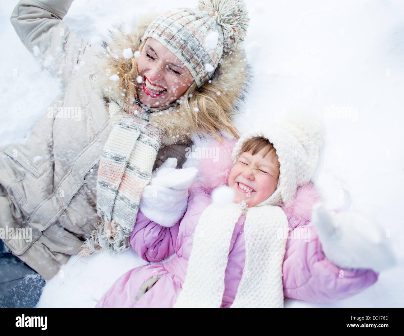Happy parent and kid lying on snow in winter outdoor Stock Photo
