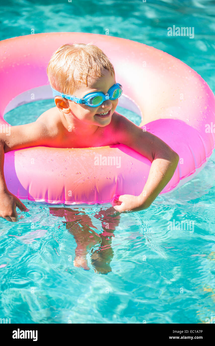 Little Kid Having Fun in Swimming Pool, with Goggles and Raft. Summer Vacation Fun. Stock Photo