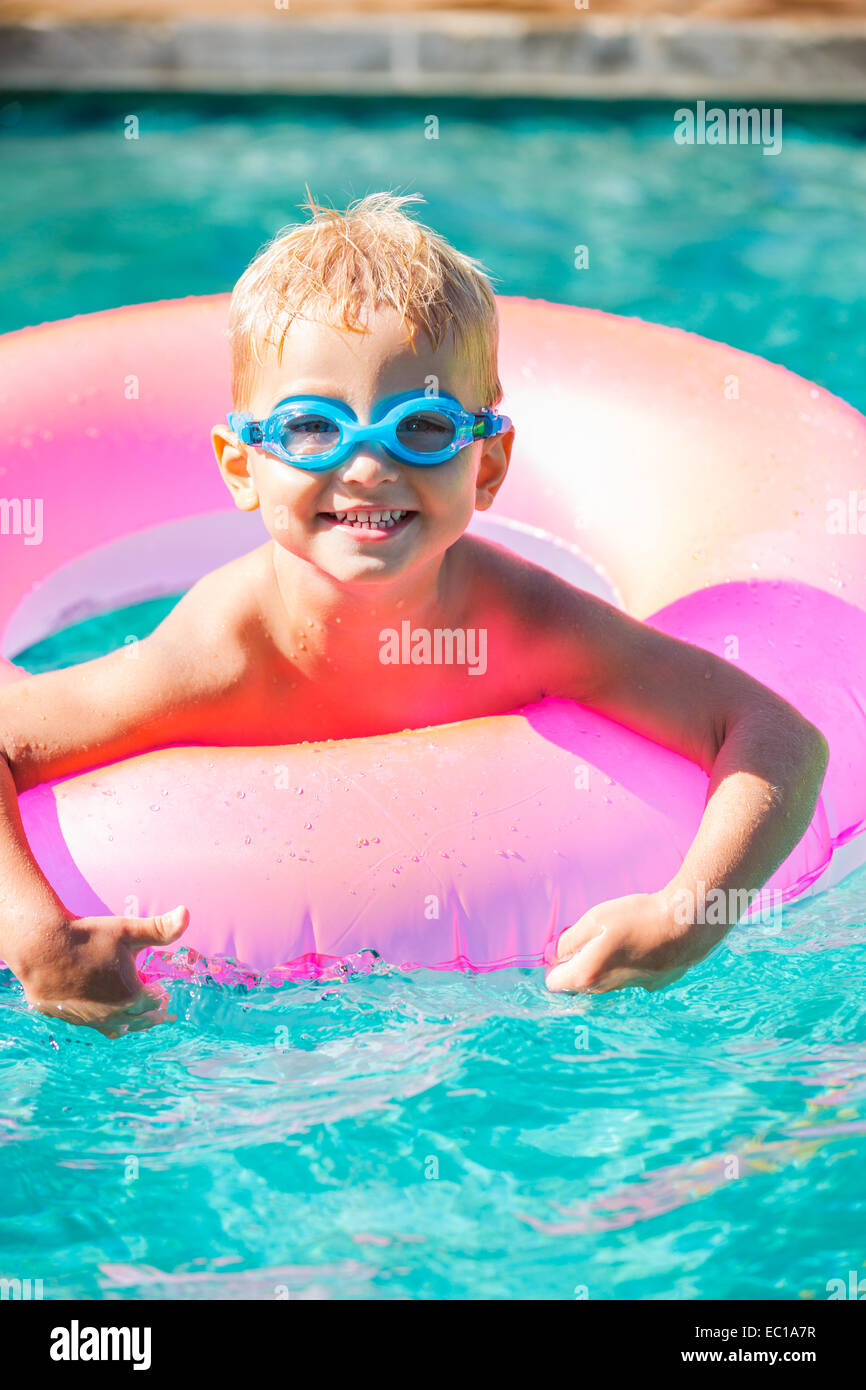 Little Kid Having Fun in Swimming Pool, with Goggles and Raft. Summer Vacation Fun. Stock Photo