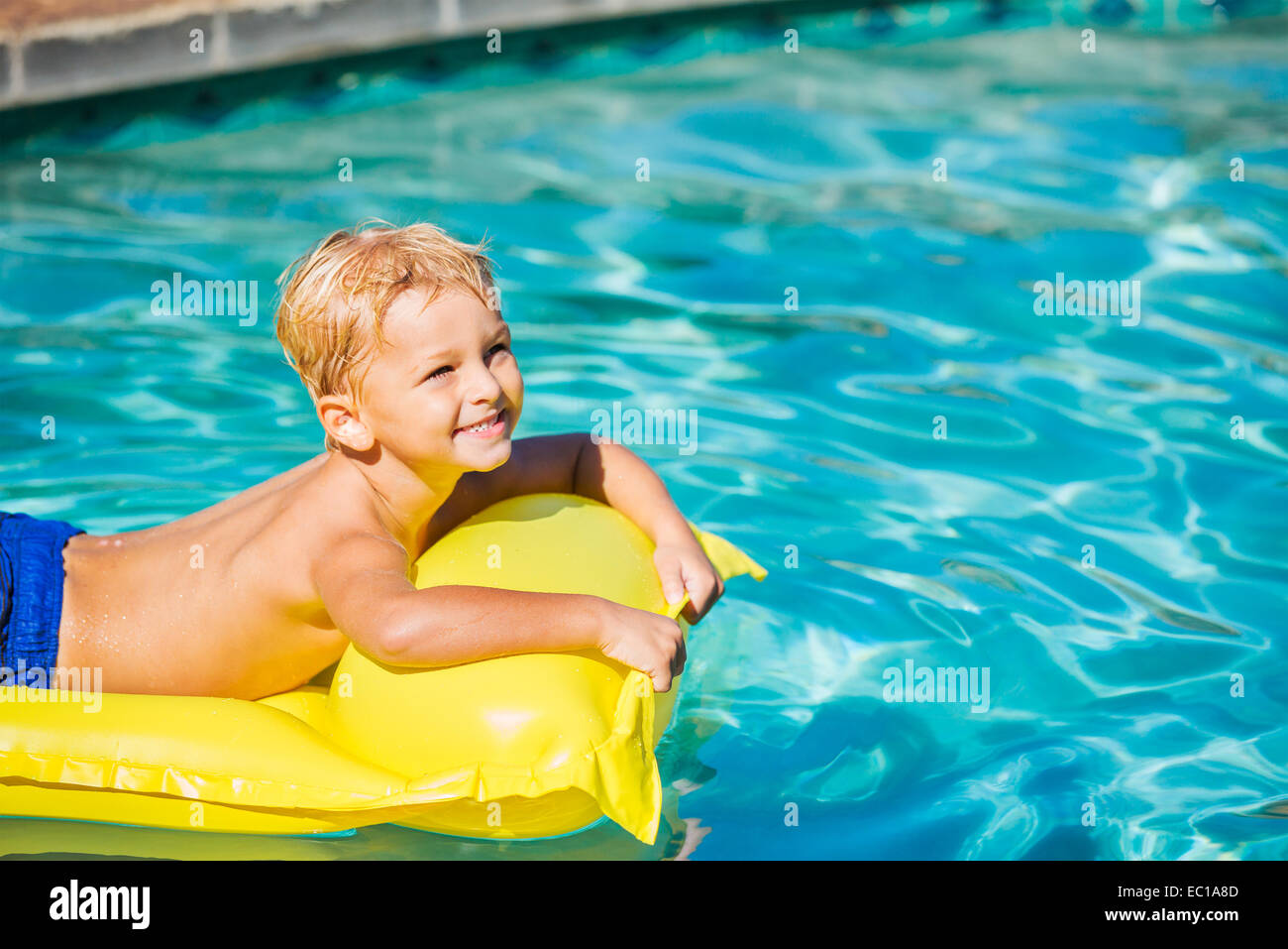 Young Boy Relaxing and Having Fun in Swimming Pool on Yellow Raft. Summer Vacation Fun. Relaxing Lifestyle Concept. Stock Photo