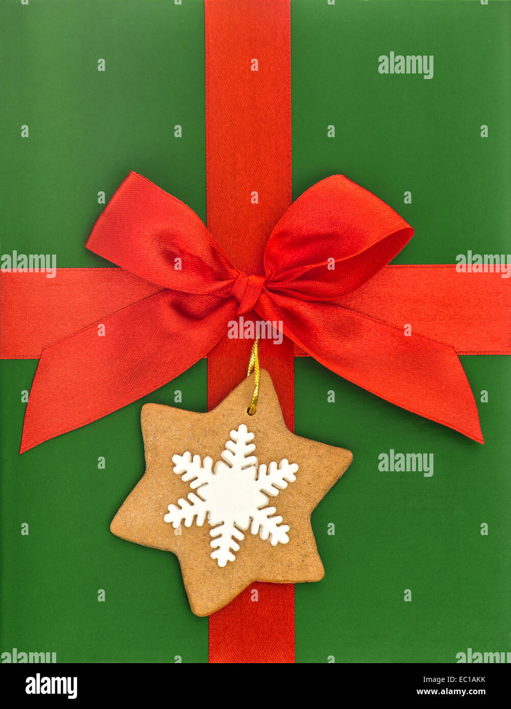 red ribbon bow with gingerbread cookie over green gift paper. holidays background Stock Photo