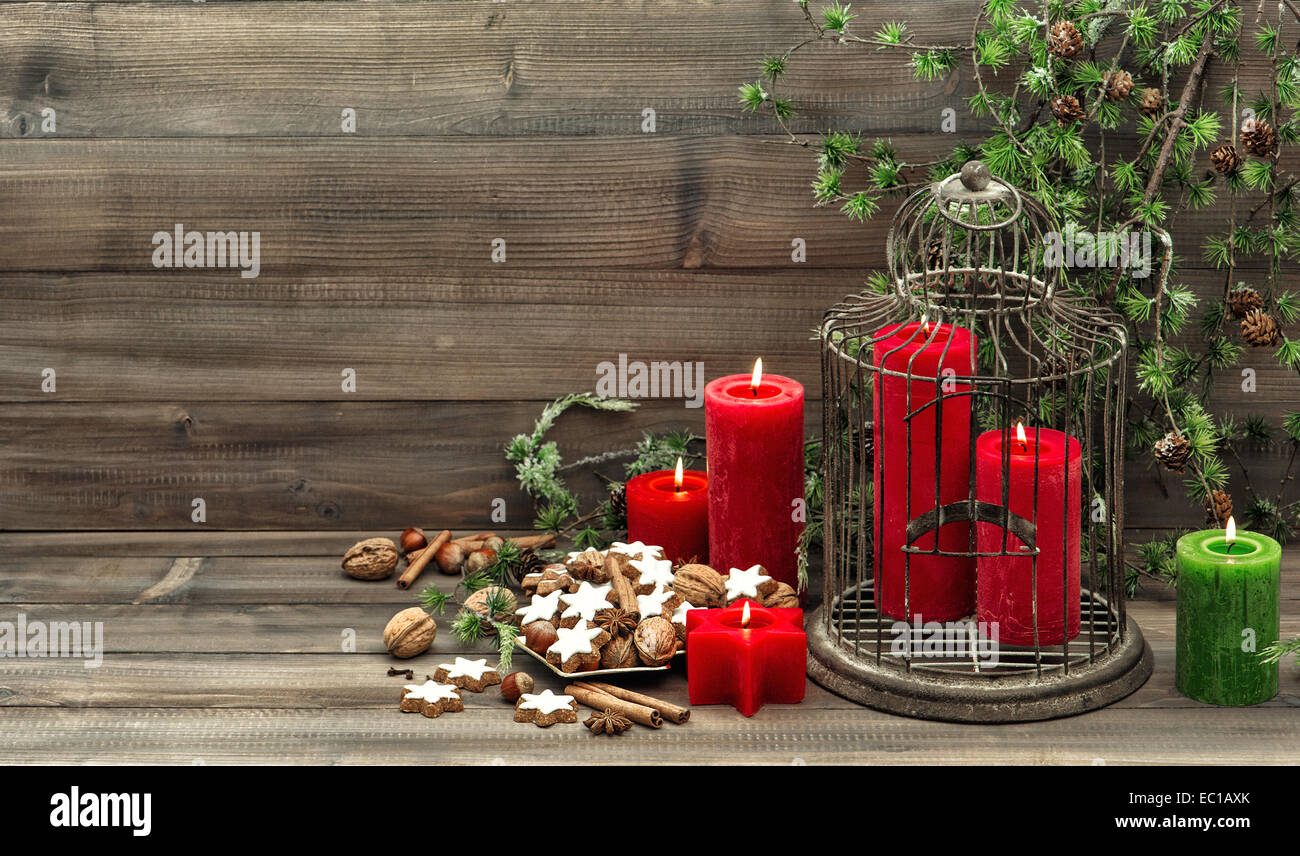 christmas decoration birdcage, red candles and pine branch. nostalgic home interior. cinnamon cookies, nuts and spieces Stock Photo