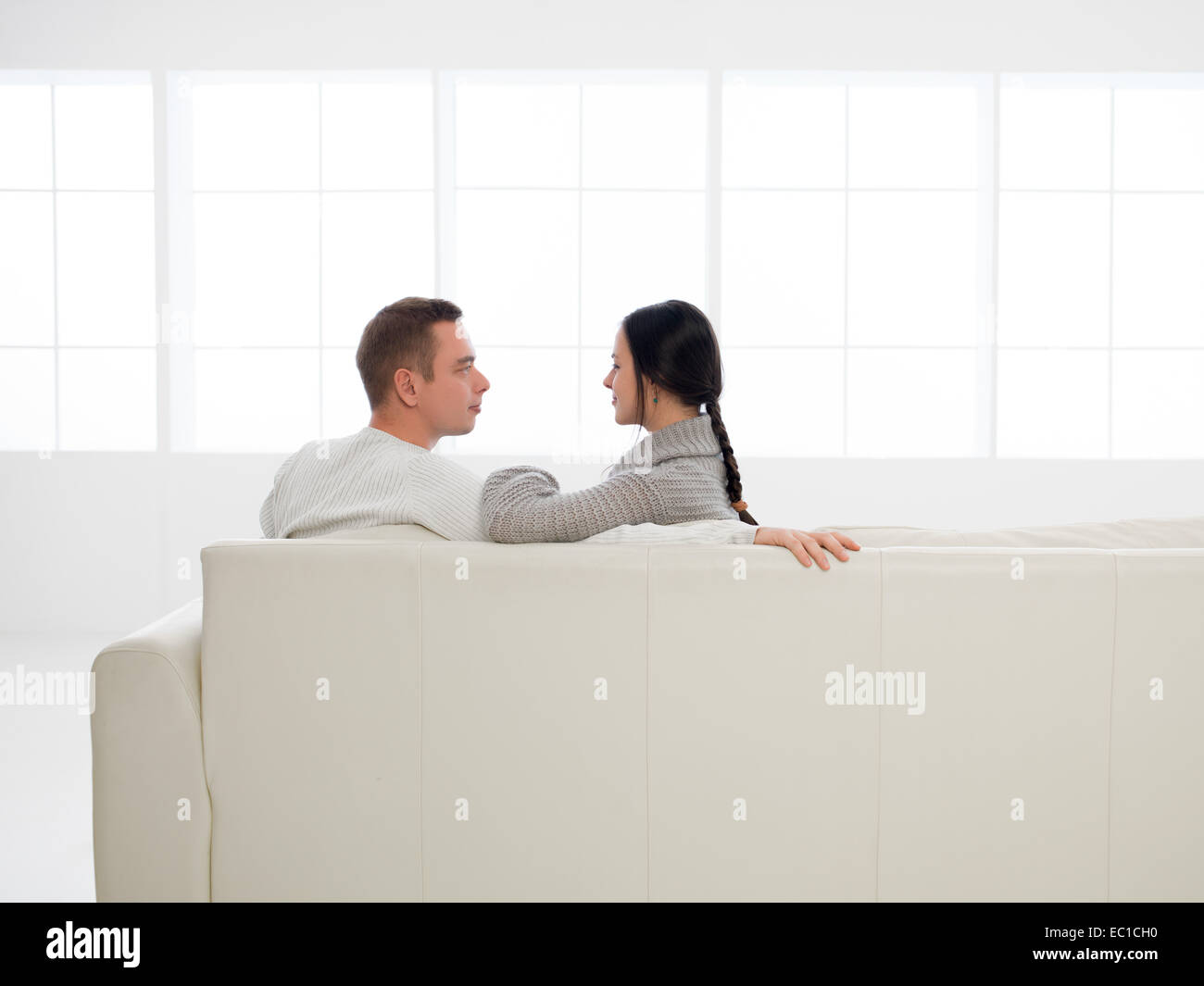 back view of young happy caucasian couple sitting on sofa in new house Stock Photo